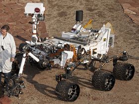 Hvis du trodde Curiosity var en søt liten Wall-E-robot, må du tro om igjen. Her står en forsker ved siden av roveren på et testområde i California.