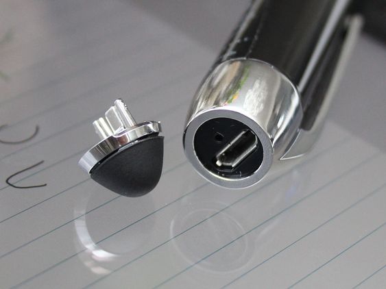 Gummiputen i enden fungerer som skjermpenn. Pennen lades via USB-kontakten som er skjult under puten.