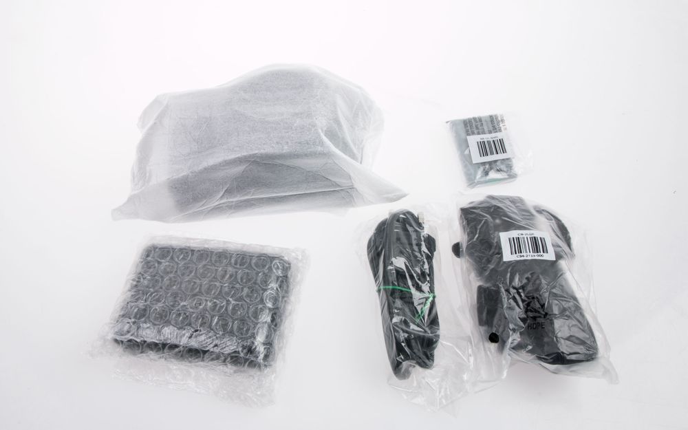 Inni filtposen finner vi kameraet, som er pakket inn i en ekstra pose. I pappesken finner vi alt det andre du ser på bildet: lader, batteri, strømkabel og reim.