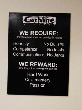 En plakat som henger på veggen hos Carbine Studios med hva de krever av sine ansatte. (Bilde: Håvard Hofstad Ruud/Gamer.no).