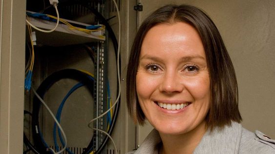 Homenet-sjef Nina Vesterby foran skapet i kjelleren der den lille boksen som leverer bredbånd til leilighetene står.