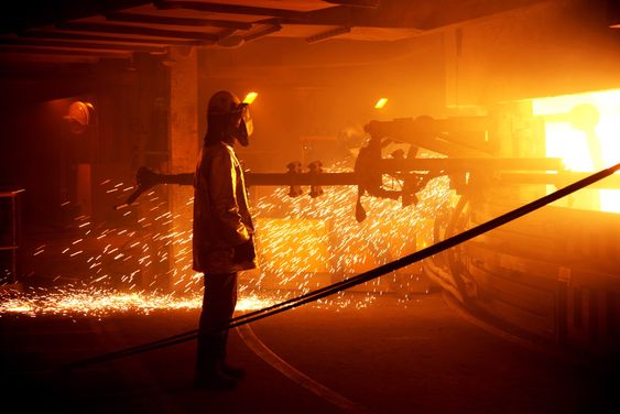 Arbeidere i flammehemmende drakter renser tappekanalene på den ombygde og miljøvennlige smelteovnen på Elkem Salten. 