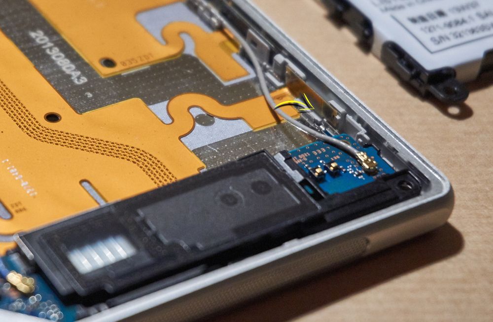 Med alle tilkoblingene klikket på plass, kunne den svarte plastdelen plasseres trygt tilbake. Det var imidlertid viktig å legge disse ledningene nøyaktig slik de var da vi åpnet telefonen. I dette tilfellet kunne ledningen ha kommet i klem da vi satte i batteriet – og vi ville mistet enten WiFi- eller telefonsignalet vårt.