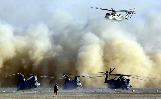 En CH-53E Super Stallion går inn for landing i Afghanistan. På rullebanen står en annen CH-53E og to CH-46E Sea Knights. 