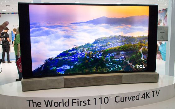 Størst: Kinesiske TCL har laget verdens største kurvede TV med sin 110 tommer. Designen er det B&Os avhoppede designsjef som står for. Han har flyttet til kina og får boltre seg i eik og betong. Denne står støtt på sine betongføtter 
