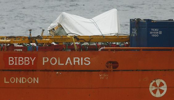 Tildekkede vrakdeler fra AS332L2-maskinen som havarerte utenfor Shetland fredag kveld, i ferd med å fraktes til land mandag formiddag. 