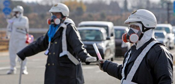 Politimenn med gassmasker leder trafikken vekk fra kjernekraftverket Fukushima Daiichi 1 under evakuering i mange kilometers radius etter radioaktive utslipp grunnet lørdagens eksplosjon ved anlegget.kjernekraft atomkraft jordskjelv tsunami japan kjernekraftverk
