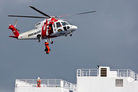 Norske, danske og svenske helikopter fløy i skytteltrafikk i området. Her er et svensk helikopter i ferd med å heise brann - og redningsmannskaper ned til det havarerte skipet.