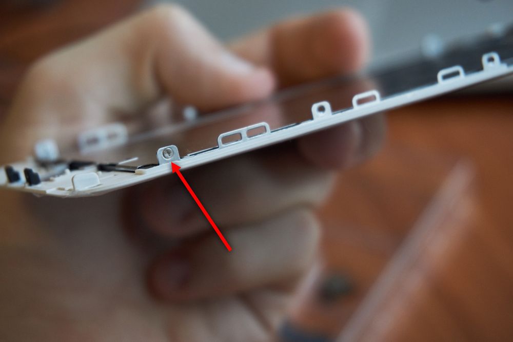 Nå gjenstod kun LCD-bakplaten. For å få ut den måtte vi først skru ut de tre skruene på hver side. Her har vi allerede tatt ut to av skruene på den ene siden.