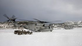 Nederlandske marineinfanterister sitter i kringvern på bakken når to amerikanske CH-53E tar av under vinterøvelsen Cold Response 2016.
