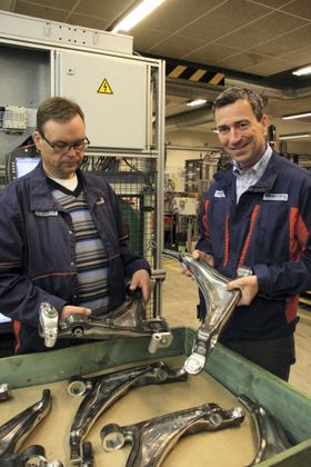 Hans Petter Kristiansen (t.v.) med ferdig montert hjuloppheng til Volvos XC 90-serie. Christopher M. Braathen med delen før den sendes inn i den robotiserte monteringslinjen.