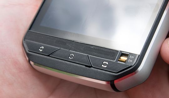 Forsiden av telefonen prydes av tre digre knapper. Hjemknappen må trykkes to ganger før skjermen går på. Rett over knappene et deksel som skjuler høyttaler og mikrofon.