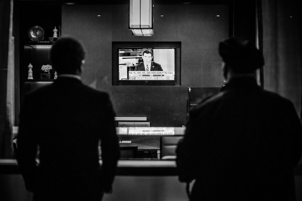 HILTON MIDTOWN, 8. NOVEMBER 2016 - KL 20.37: En mann jeg tror er Secret Service-agent og en mann jeg er bra sikker er politimann ser på Fox News på en TV-skjerm inne på Midtown Hilton. Det er for tidlig å kåre en vinner i de fleste vippestater, men Donald Trump gjør det bedre enn forventet.