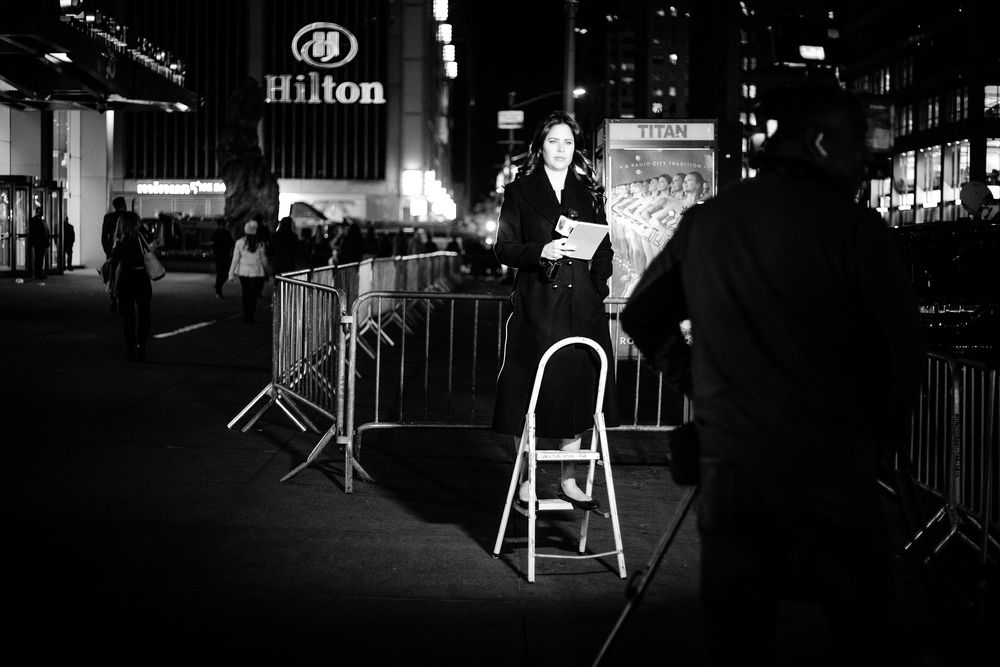 HILTON MIDTOWN, 8. NOVEMBER 2016 - KL 21.21: Alt for å oppnå den perfekte komposisjon. En kvinnelig reporter - som mange andre reportere utenfor Hilton Midtown - bruker en stige for å stå i høyde med skilten til hotellet.