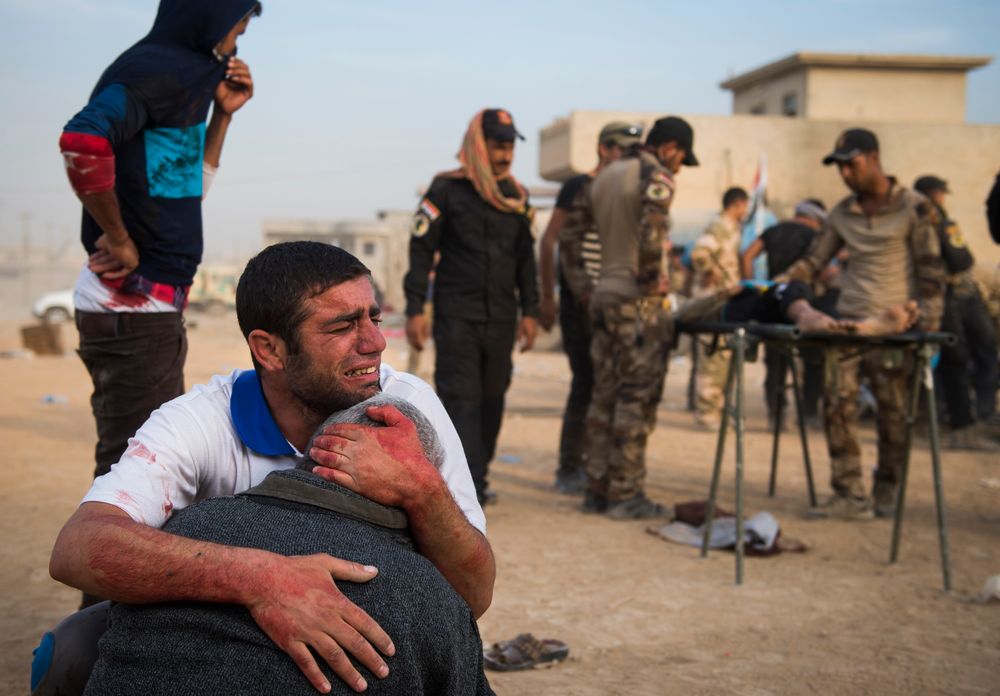 Fortvilelse: Far og bestefar til 15 år gamle Shafiq sørger ved siden av guttens livløse kropp, ved et feltsykehus i Mosul. Shafiq ble drept i et IS-angrep under kamper med irakiske styrker i Nord-Irak.