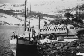 LIVSÅRE: Mjølkebåten til Bygstad meieri gjekk tre gonger i veka frå gardane på Øyna og i Fossedalen. Oddleif Stenseth står på båten og hjelper til med lastinga.