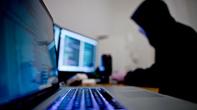 Hacker foran dataskjermer. Illustrasjonsfoto.
