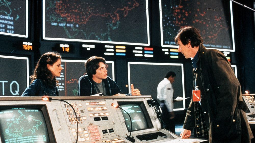 Scene fra WarGames-filmen med skuespillerne Ally Sheedy, Mathew Broderick og John Wood. I bakgrunnen sees noen av de store skjermene til WOPR-datamaskinen til NORAD.