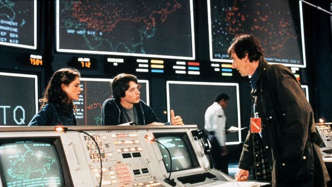 Scene fra WarGames-filmen med skuespillerne Ally Sheedy, Mathew Broderick og John Wood. I bakgrunnen sees noen av de store skjermene til WOPR-datamaskinen til NORAD.