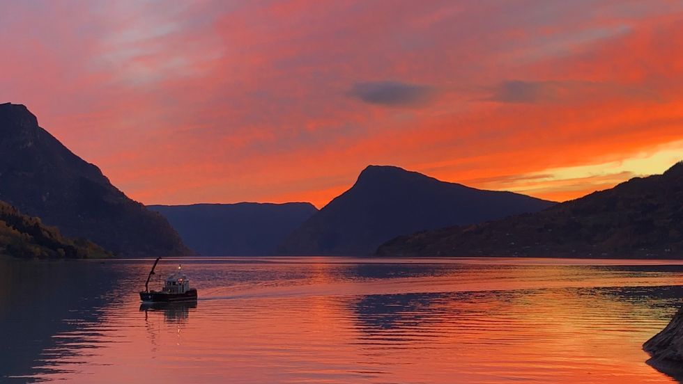 RAUDT: Lustrafjorden og Molden badar i raudt lys frå himmelen.