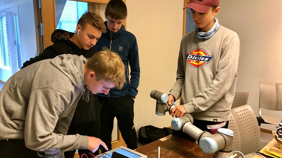 KONSENTRERT ARBEID: Her prøver elevane å få robotarmen til å forstå korleis dei vil at han skal røra på seg.