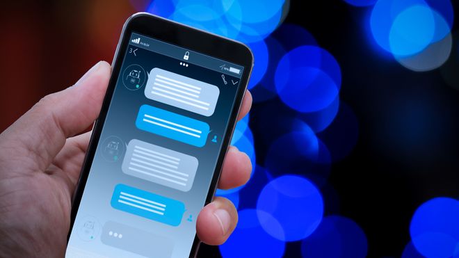 Chatbot med snakkebobler på en mobiltelefon i hånd.