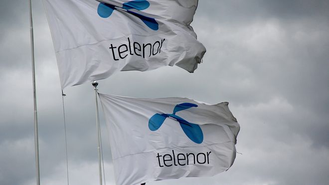 Telenor-flagg mot mørk himmel, mørke skyer.
