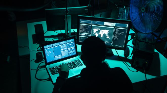 To hackere sitter i mørket foran PC-er.
