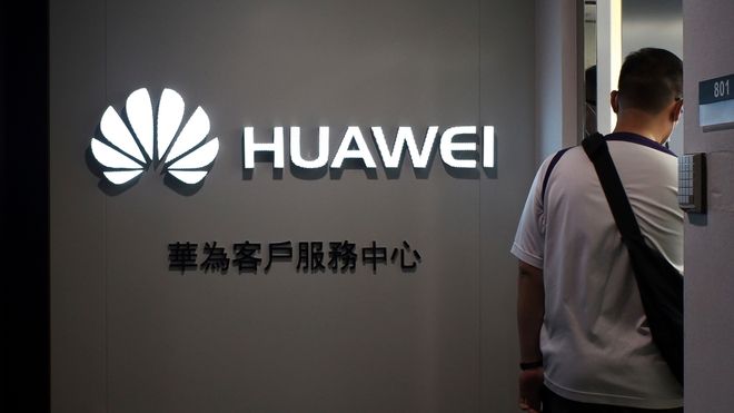 En mann går forbi en Huawei-logo
