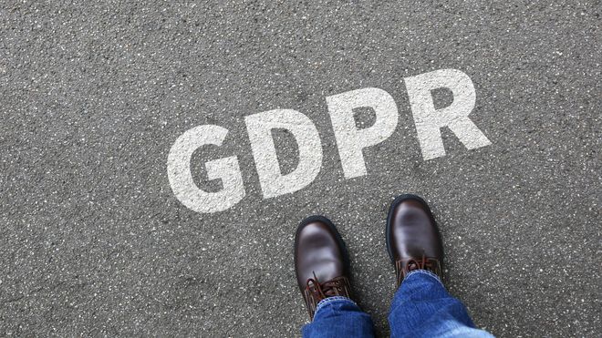 Teksten "GDPR" skrevet på asfalten foran føttene til en person.