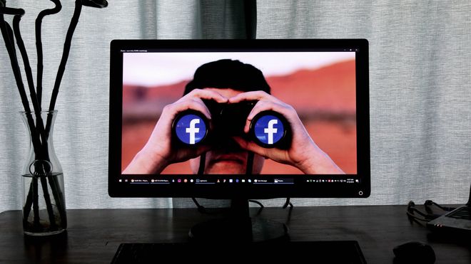PC-skjerm. På skjermen vises en person som ser på deg med en kikkert med Facebook-logoen.