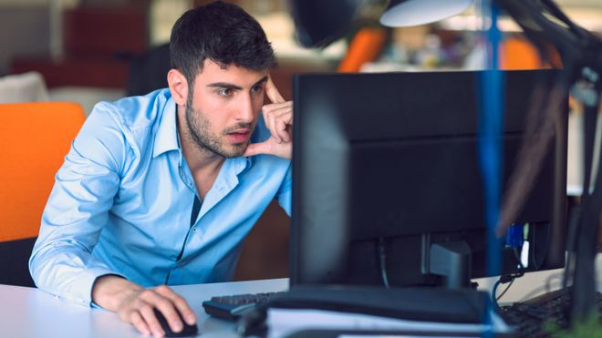 Mann stirrer konsentrert på en PC-skjerm.