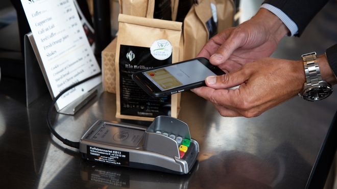 Mann betaler med mobiltelefonen på bankterminal.