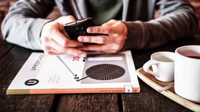 Nærbilde av noen som bruker mobiltelefon på en kafe.