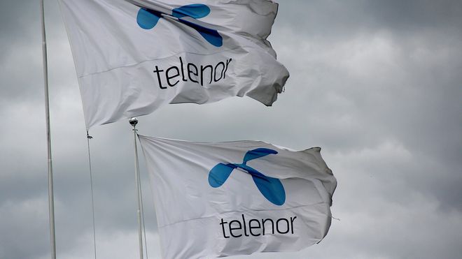 Telenor-flagg mot mørk himmel, mørke skyer.