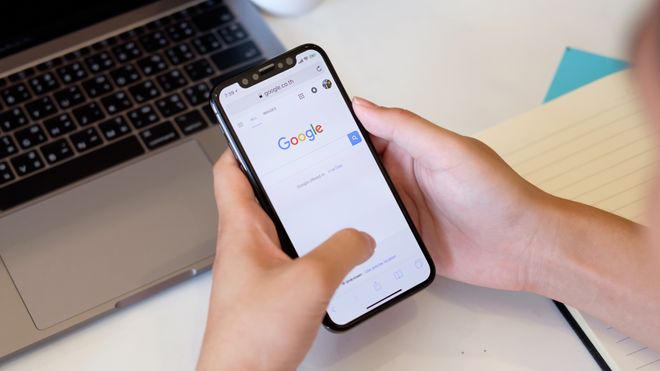 Nærbilde av noen som holder en iPhone med Google-søkemotoren på skjermen.