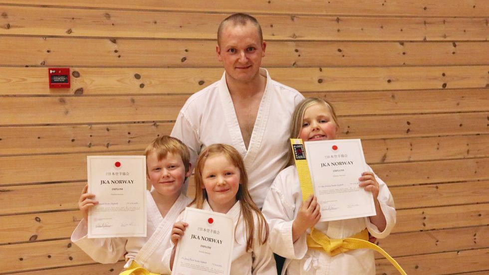 STOLTE: Andreas (8, t.v.), Jenny Marie (7, midten) og Ida Emilie (10, t.h.) Førde Systad var stolte over å ha sikra seg gult belte i karate måndag. Bak står far Jan André Førde Systad.