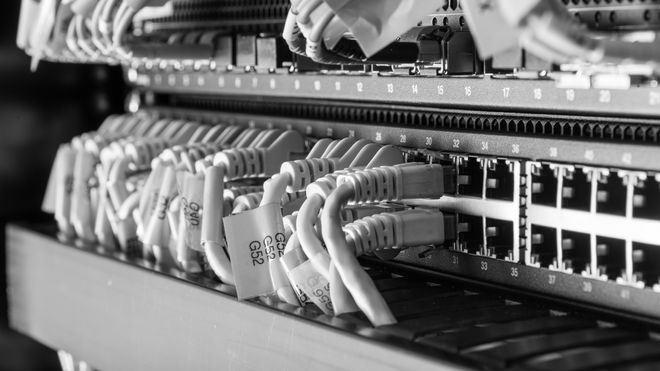 Nærbilde av nettverkssvitsjer med et stort antall Ethernet-kabler koblet til.