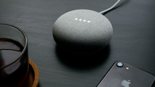 En Google Home-enhet ved siden av en Apple-mobiltelefon.