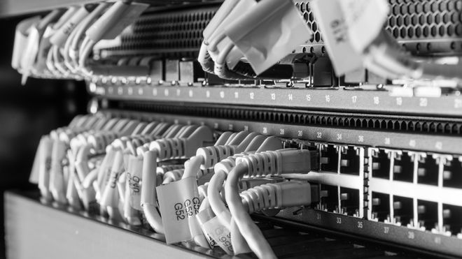 Nærbilde av nettverkssvitsjer med et stort antall Ethernet-kabler koblet til.