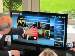 Her er telefonen koblet til en TV ved hjelp av en dokk. Kobler du strøm til dokken, så kan du bruke løsningen som Android-PC. En egen fjernkontroll følger med, eller du kan koble USB-mus og tastatur til dokken. Men du kan ikke betjene skjermen med fingrene slik det ser ut som denne karen forsøker.