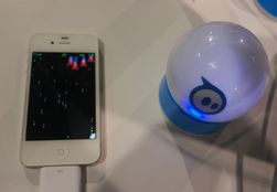En Sphero-ball i ladekrybbe ved siden av en iPhone.