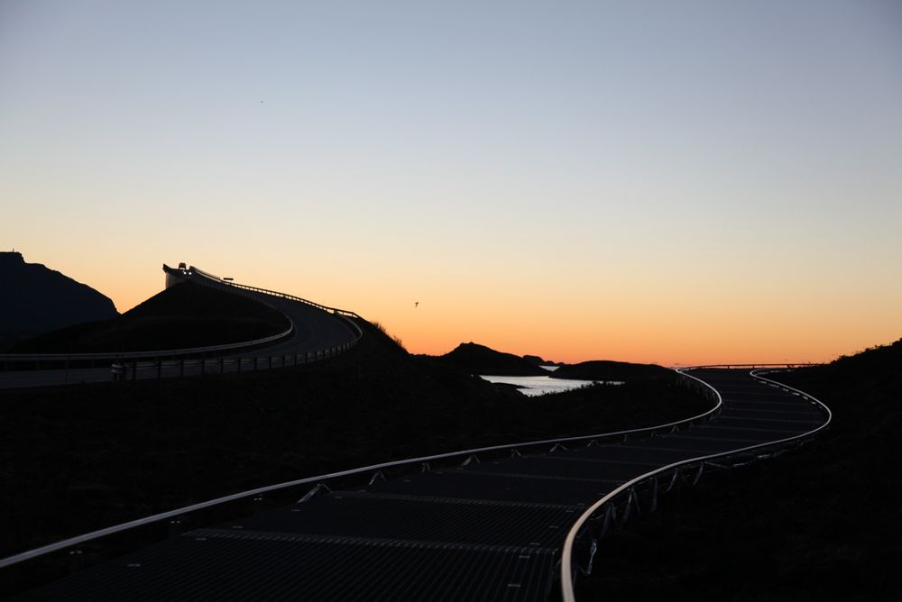 Atlanterhavsvegen – en stor turistmagnet som Nasjonale turistveger har satset mye på. Bildet viser Storseisundbrua (t.v.) og de «svevende stiene» på Eldhusøya til høyre, mens nattemørket inntar havlandet. (Foto: Kjell Herskedal)