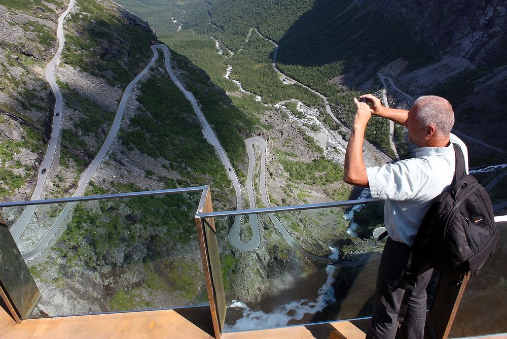 En turist tar bilder fra utsiktspunktet på toppen av Trollstigveien. 8. mai er det åpning. (Foto: Kjell Herskedal)