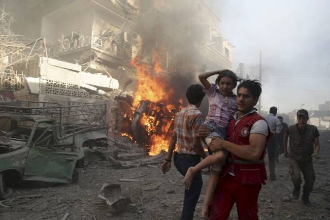SYRIA: Hjelp til dei borgarkrigsramma i Syria står på agendaen hos mange av dei store hjelpeorganisasjonane denne jula. På biletet ber ein Raude Halvmåne-tilsett ei jente vekk frå eit bombeangrep.
