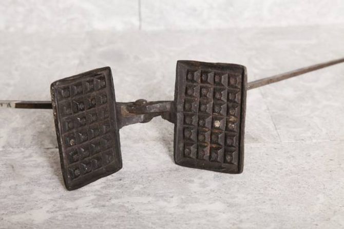 Eit gammalt vaffeljern. Slike fanst her i landet allereie på 1600-talet. Dei var visstnok relativt enkle å lage og det gjekk med lite jern, slik at fleire kunne ha råd til å skaffe seg denne «moderne» kjøkenreiskapen. Foto frå boka: Bjarne Fossøy.