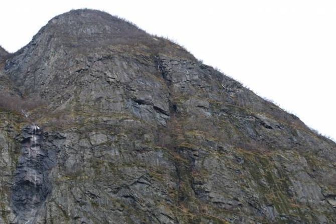 HER: Fem av sauene står på eitt av hyllepartia eit stykkje til høgre for fossen, eitt lam står på eit hylleparti rett til høgre for fossen. Bergingsmannskapet skal ta seg over toppen på biletet og ned gjelet. Anten vil dei få med sauene same veg tilbake, eller prøva å ta seg rett ut til høgre via hyllepartiet ein ser, men dei må undersøka om det er farbart her først.
