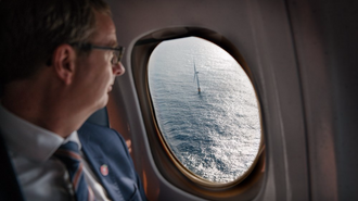 Olje og energiminister Terje Søviknes ser ut av flyvinduet på en av de fem flytende vindturbinene som utgjør Hywind Skottland.