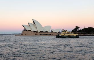 Sydney Operahus i solnedgang, sett fra sjøsiden. Fergen til Manly i forgrunnen.