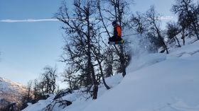 Mann hoppar på ski i laussnøen.